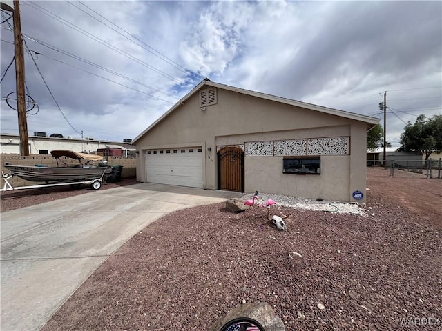 1481 E Topaz Cir Unit 2, Fort Mohave, AZ 86426 - view of side of home with an attached garage, stucco siding, driveway, and fence
