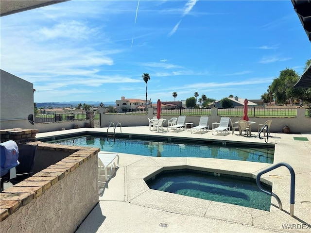 pool with fence, a hot tub, and a patio