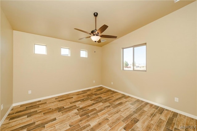 empty room with lofted ceiling, light wood finished floors, ceiling fan, and baseboards