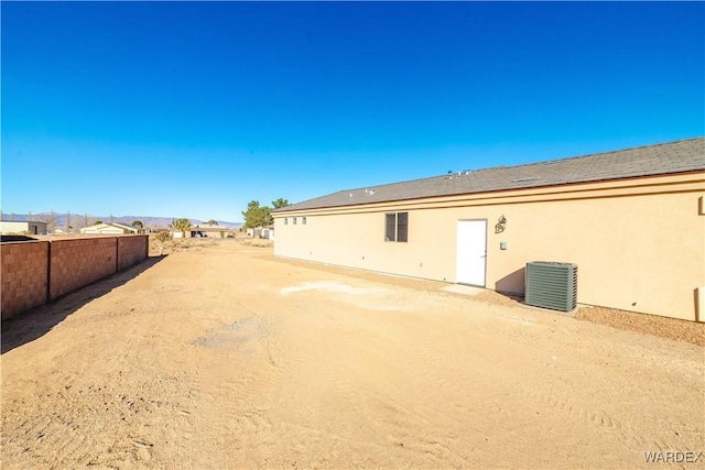 back of property with central AC, fence, and stucco siding