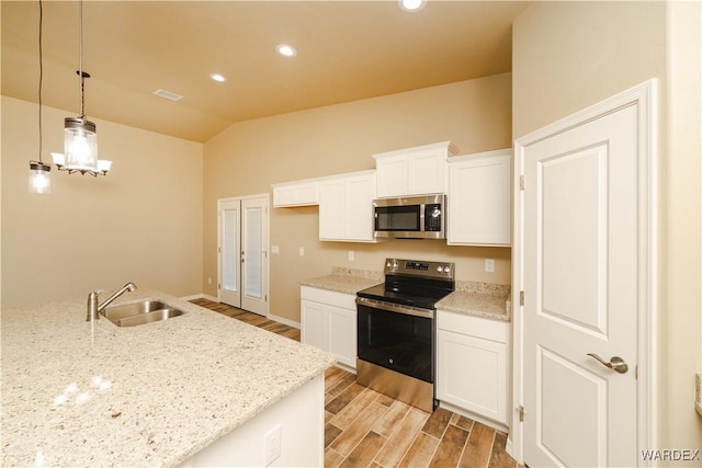 kitchen featuring appliances with stainless steel finishes, decorative light fixtures, wood finish floors, white cabinetry, and a sink