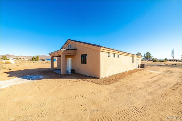 view of side of home with central AC and stucco siding