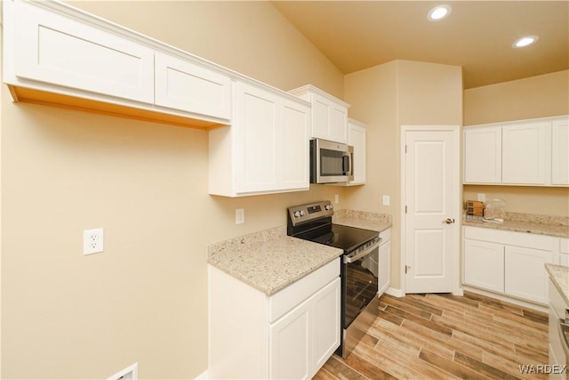 kitchen with white cabinets, light stone countertops, stainless steel appliances, wood finish floors, and recessed lighting