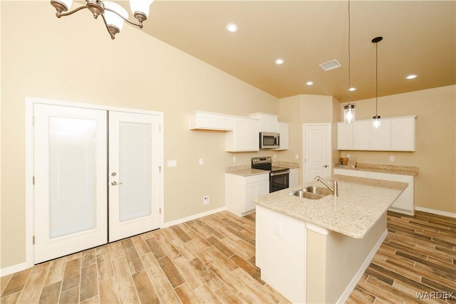 kitchen featuring wood finish floors, stainless steel appliances, visible vents, white cabinetry, and a sink