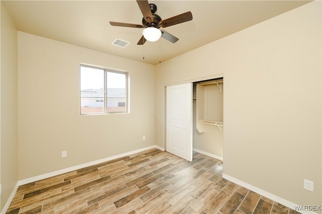 unfurnished bedroom with a closet, visible vents, a ceiling fan, wood finished floors, and baseboards