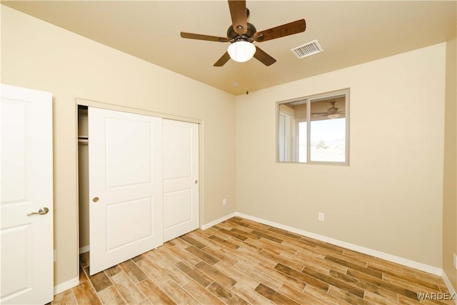 unfurnished bedroom with a closet, visible vents, ceiling fan, light wood-type flooring, and baseboards