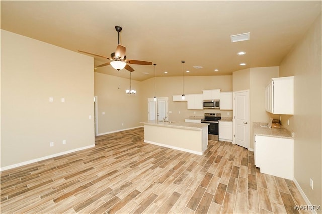 kitchen featuring stainless steel appliances, light countertops, visible vents, light wood-style floors, and open floor plan