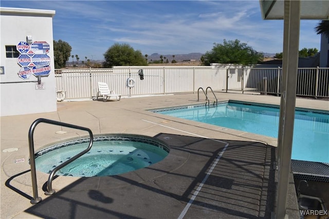 community pool with a patio area, fence, and a hot tub