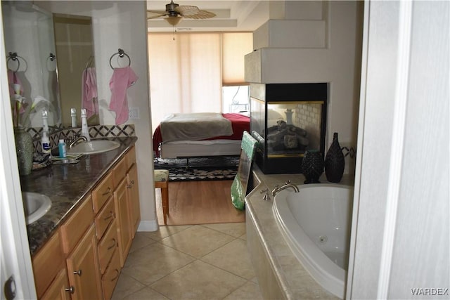 bathroom featuring double vanity, a tub with jets, ensuite bathroom, tile patterned flooring, and a sink