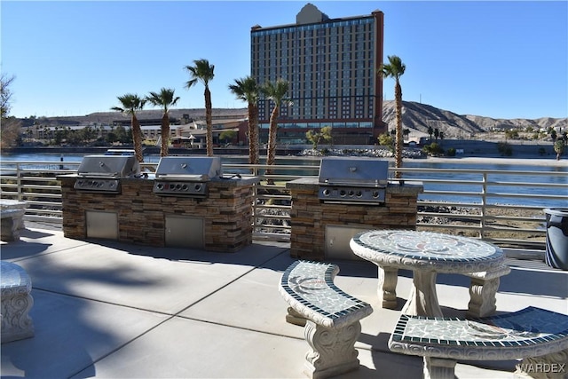 view of patio featuring exterior kitchen, area for grilling, and a water and mountain view