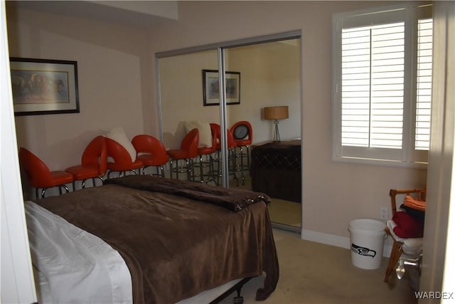 bedroom featuring light carpet, a closet, and baseboards