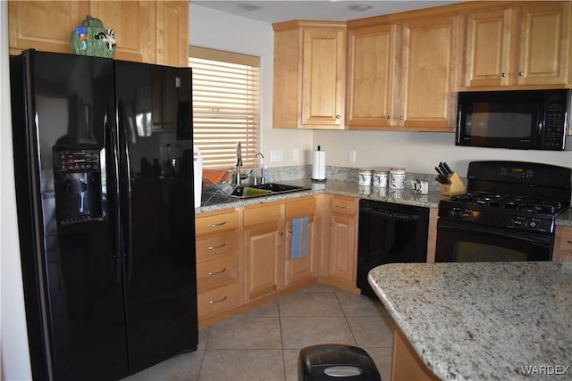 kitchen with light stone counters, light tile patterned flooring, a sink, and black appliances