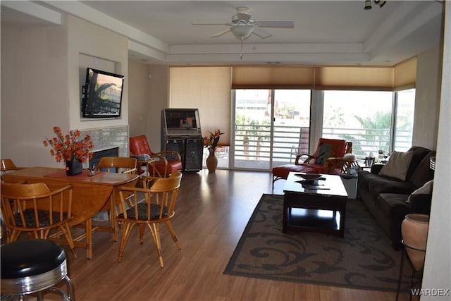 living area with ceiling fan, a fireplace, and wood finished floors