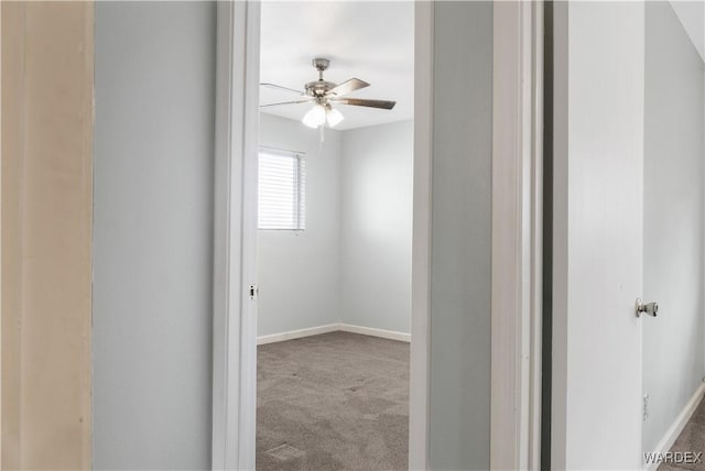 carpeted spare room featuring ceiling fan and baseboards