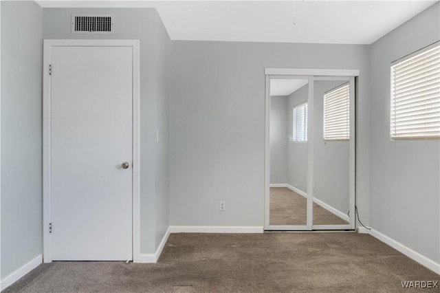 unfurnished bedroom featuring carpet floors, a closet, visible vents, and baseboards