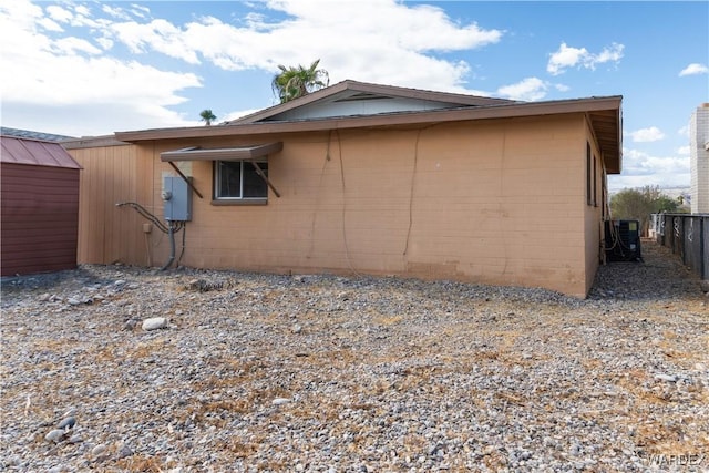 view of side of property with central AC unit, fence, and concrete block siding