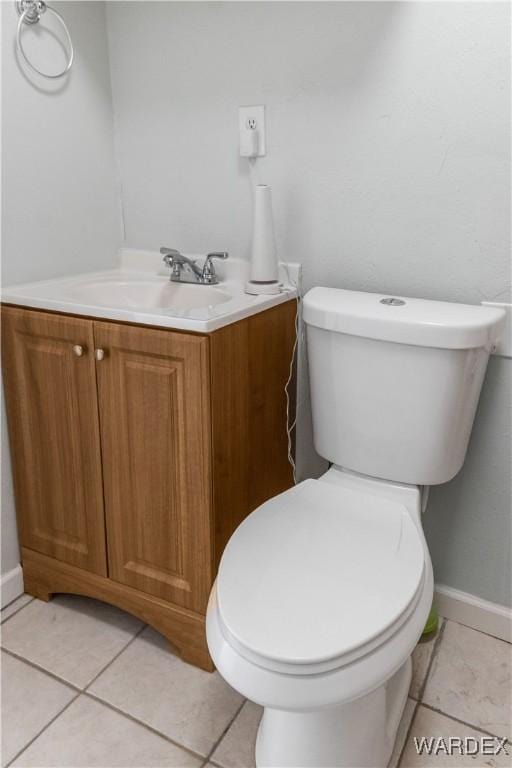 half bath with toilet, tile patterned flooring, baseboards, and vanity