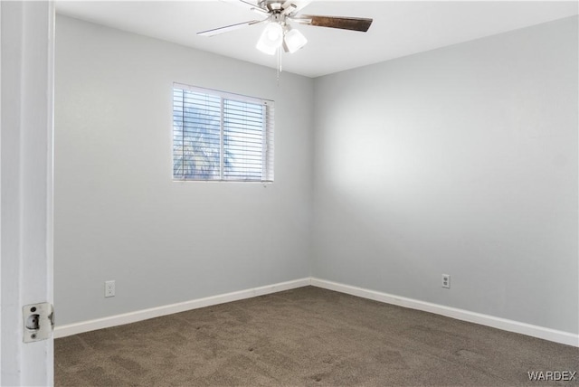 spare room with baseboards, dark colored carpet, and a ceiling fan