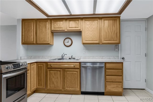 kitchen with appliances with stainless steel finishes, brown cabinets, light countertops, and a sink