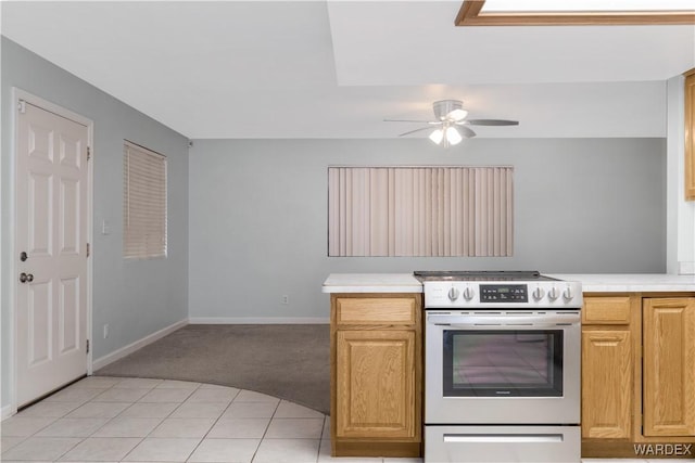 kitchen with light countertops, stainless steel electric range, a ceiling fan, and baseboards