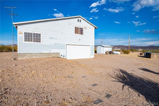 rear view of house with dirt driveway, a mountain view, and a garage