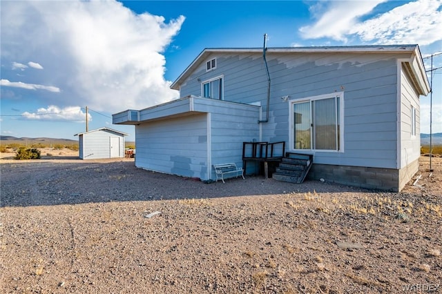 rear view of property with entry steps, an outdoor structure, and a storage shed