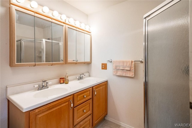 bathroom with double vanity, a sink, a shower with shower door, and tile patterned floors