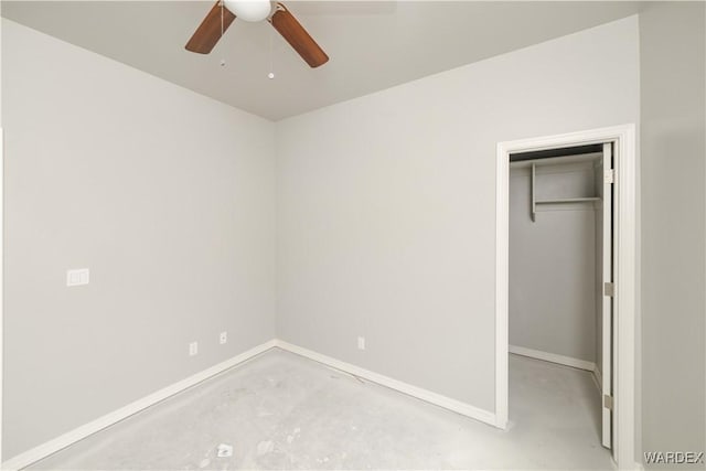 unfurnished bedroom with a walk in closet, a closet, ceiling fan, concrete flooring, and baseboards