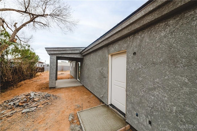 view of side of property with a patio area, fence, and stucco siding