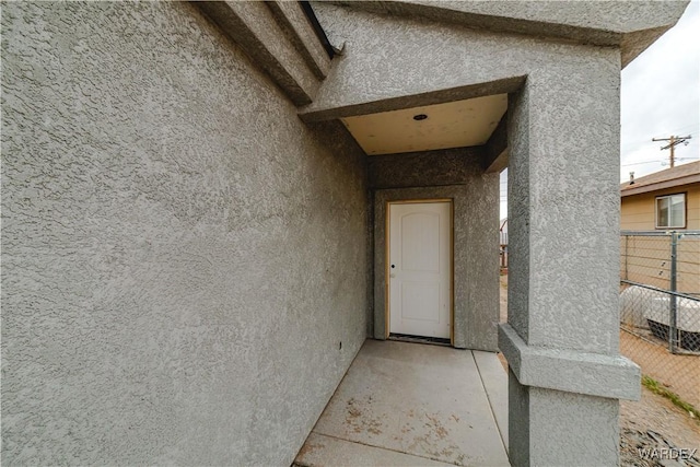 doorway to property with fence and stucco siding