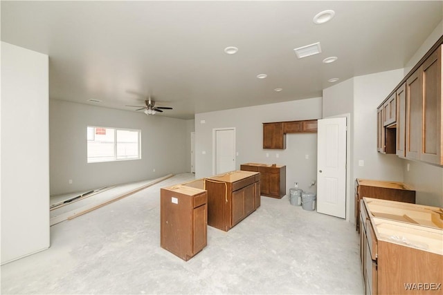 kitchen featuring visible vents, unfinished concrete flooring, ceiling fan, brown cabinets, and a center island