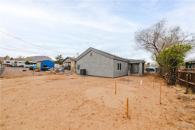 back of property featuring central AC, fence, and stucco siding