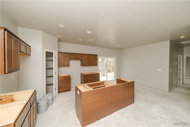 kitchen featuring concrete flooring, brown cabinets, visible vents, and a center island