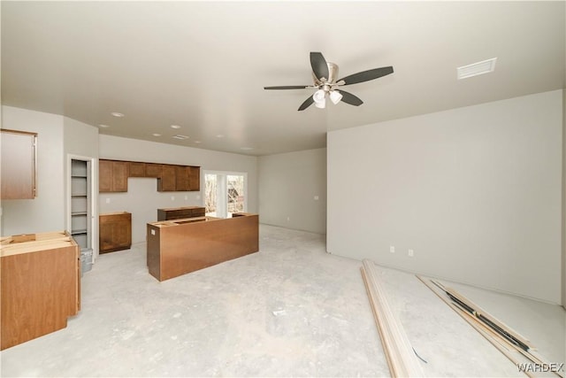 kitchen with a ceiling fan, brown cabinetry, and concrete flooring