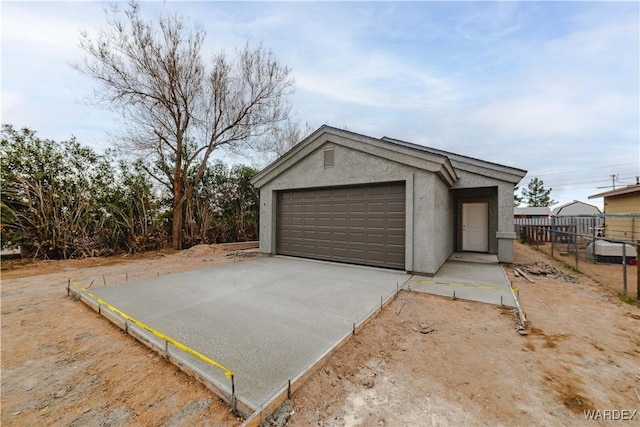 garage featuring driveway and fence