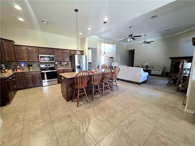 4132 Monte Silvano Ct, Kingman, AZ 86401 - kitchen featuring stainless steel appliances, ornamental molding, tasteful backsplash, dark brown cabinets, and a kitchen island with sink