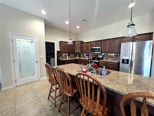 4132 Monte Silvano Ct, Kingman, AZ 86401 - kitchen with appliances with stainless steel finishes, dark brown cabinetry, backsplash, and a kitchen bar