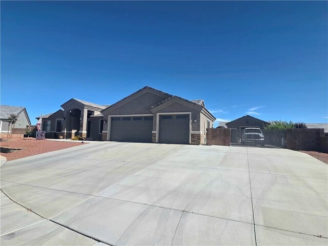 4132 Monte Silvano Ct, Kingman, AZ 86401 - ranch-style house featuring an attached garage, concrete driveway, stone siding, stucco siding, and a gate