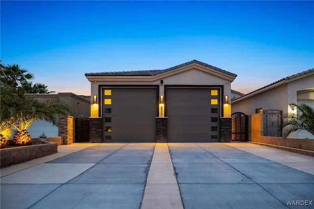 view of front of house with stucco siding, driveway, a tile roof, a gate, and a garage