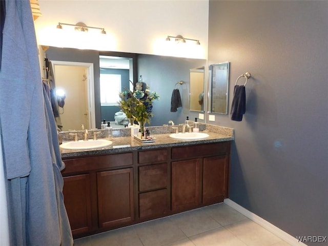 bathroom with tile patterned flooring, a sink, baseboards, and double vanity