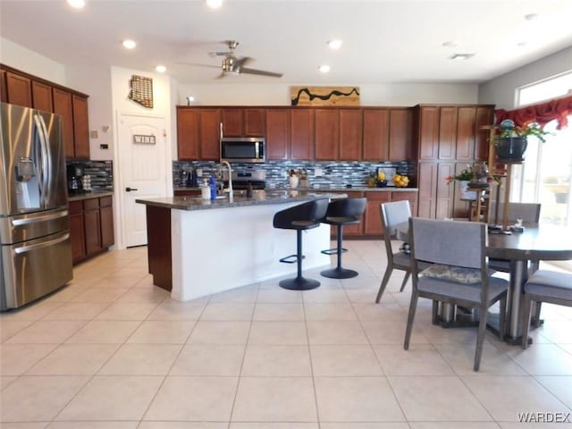 kitchen featuring light tile patterned floors, stainless steel appliances, recessed lighting, backsplash, and a kitchen island with sink