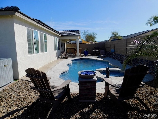 view of swimming pool featuring a pool with connected hot tub, a fenced backyard, a patio, and central air condition unit