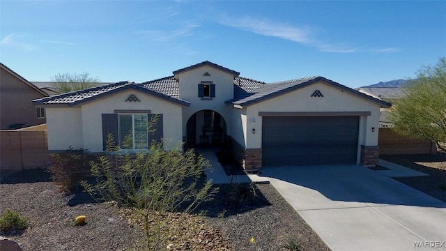 mediterranean / spanish-style house featuring a garage, a tiled roof, concrete driveway, and stucco siding