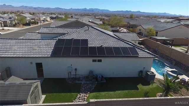 back of property featuring a tile roof, a residential view, a mountain view, and solar panels