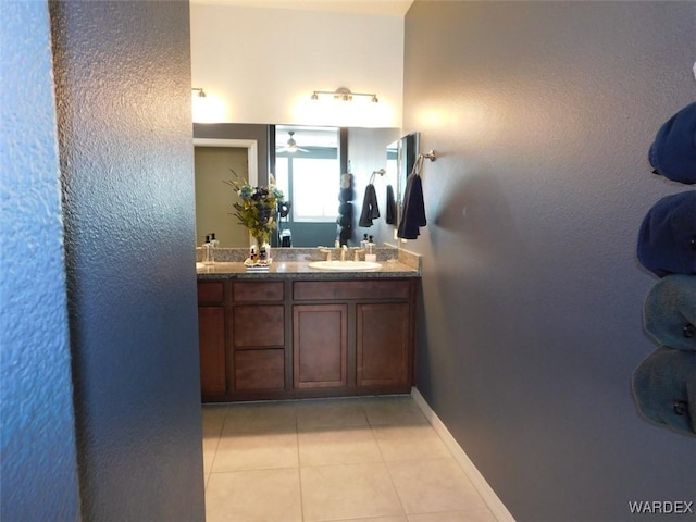 full bathroom with double vanity, tile patterned flooring, a sink, and baseboards