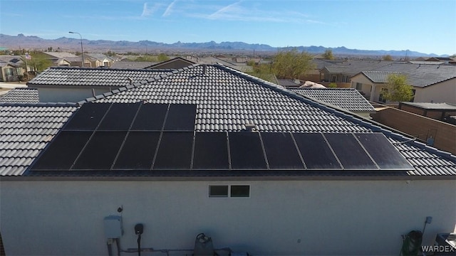 exterior space featuring a mountain view, a residential view, and roof mounted solar panels