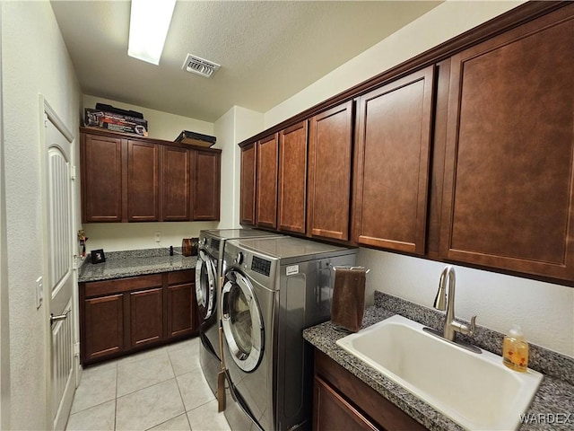 laundry room featuring light tile patterned floors, cabinet space, visible vents, washing machine and dryer, and a sink