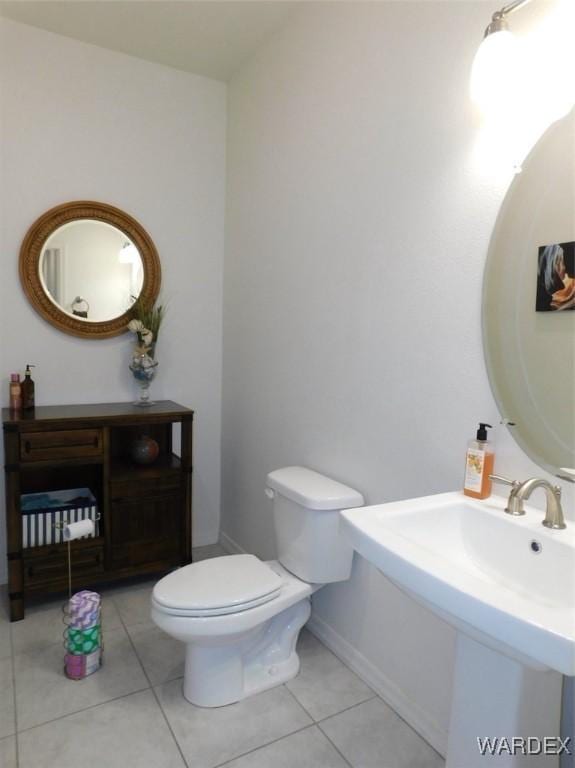 bathroom with toilet, baseboards, and tile patterned floors