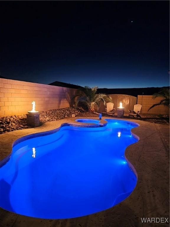 pool at twilight featuring an outdoor fire pit, a patio area, a fenced backyard, and a pool with connected hot tub