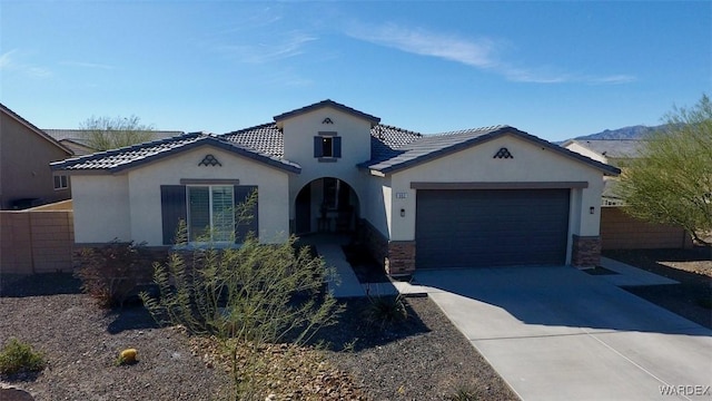 mediterranean / spanish-style home featuring driveway, a tiled roof, an attached garage, and stucco siding